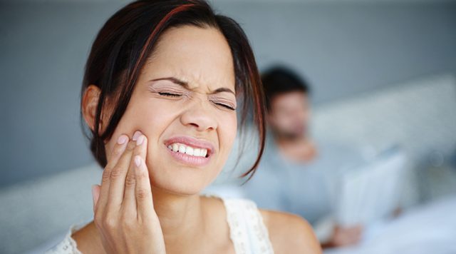 Woman winces from tooth pain
