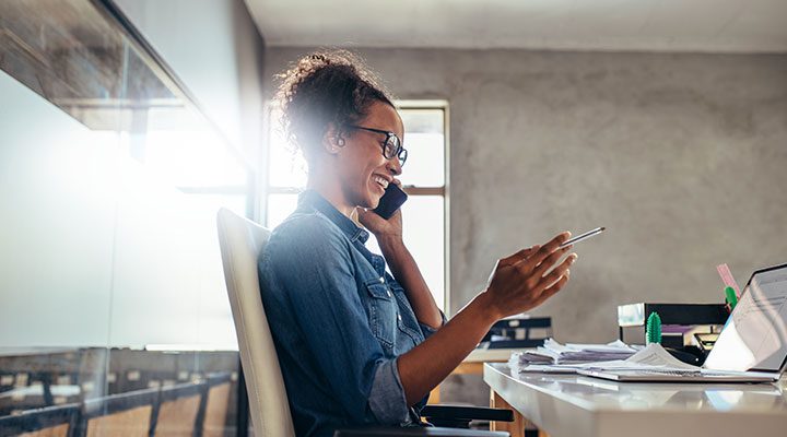 Woman on phone, working at a desk with lots of paperwork