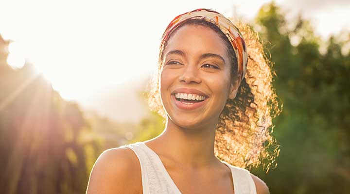 Smiling woman standing outside with the sun behind her