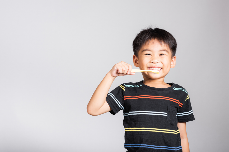 Child smiling and brushing his teeth.